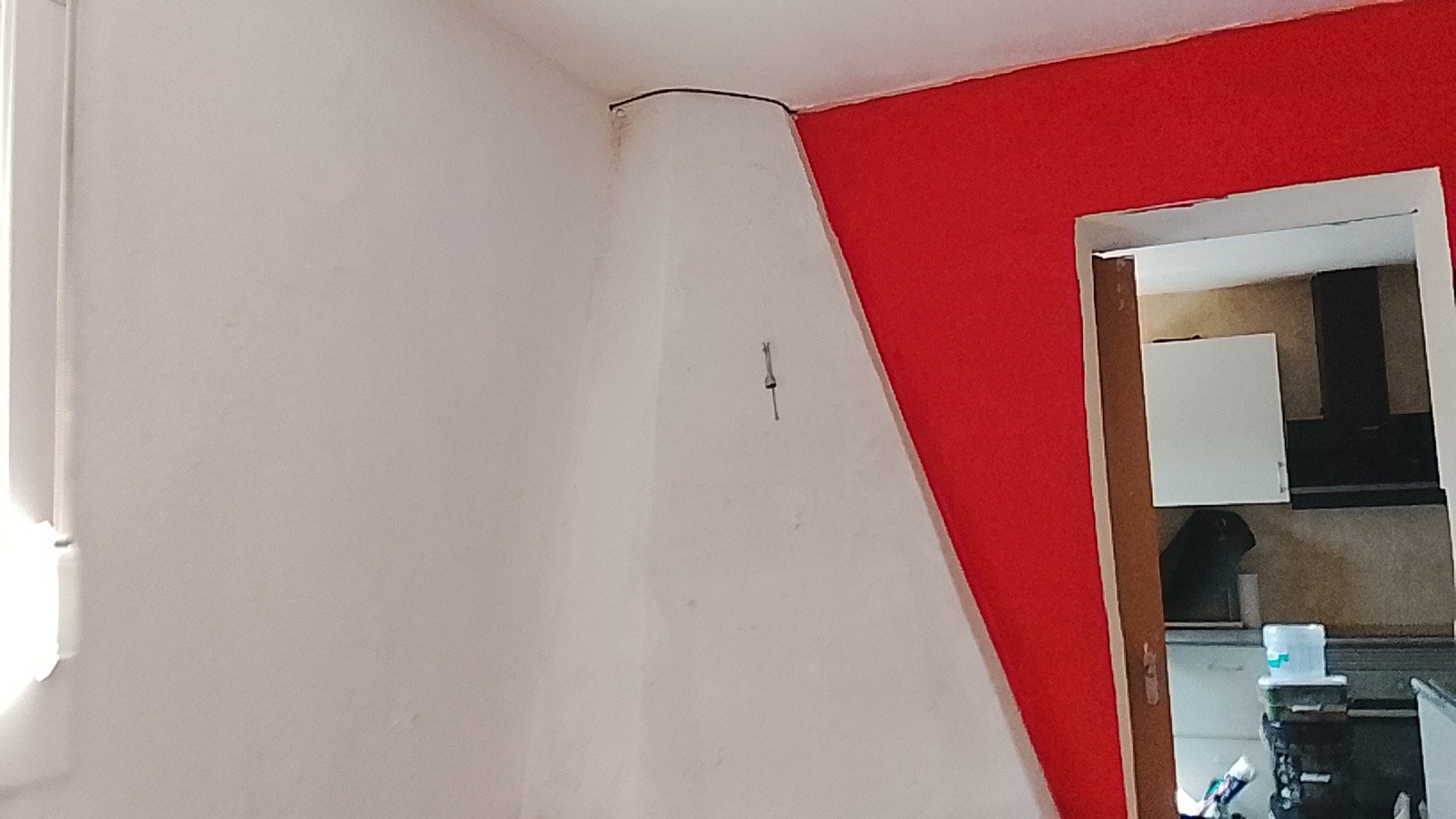 Salón con pared de acento roja y resto en blanco, trabajo limpio