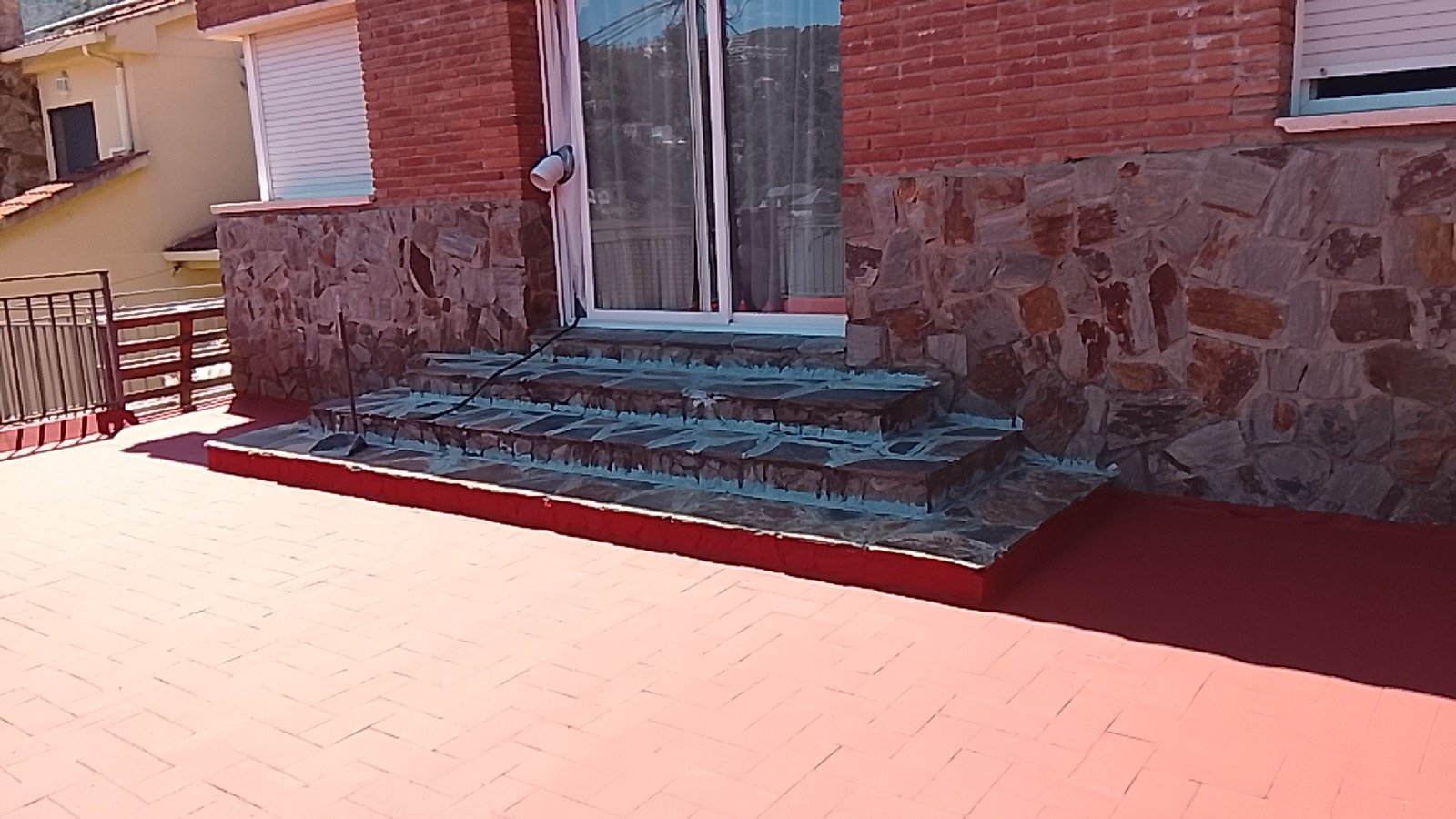 Terraza con escalera de piedra y suelo rojo terminado