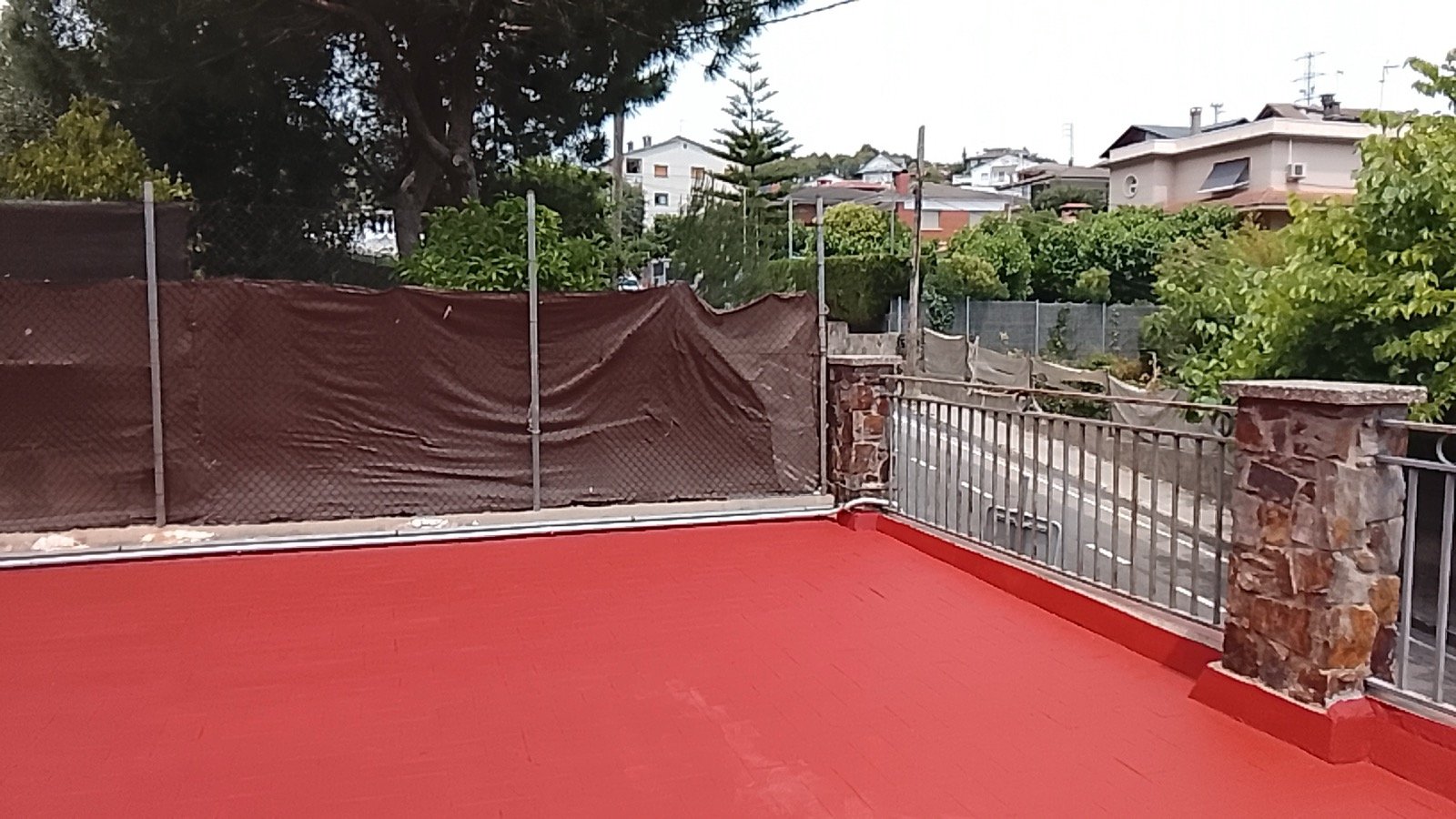 Terraza exterior con suelo rojo teja recién aplicado y protegida del agua